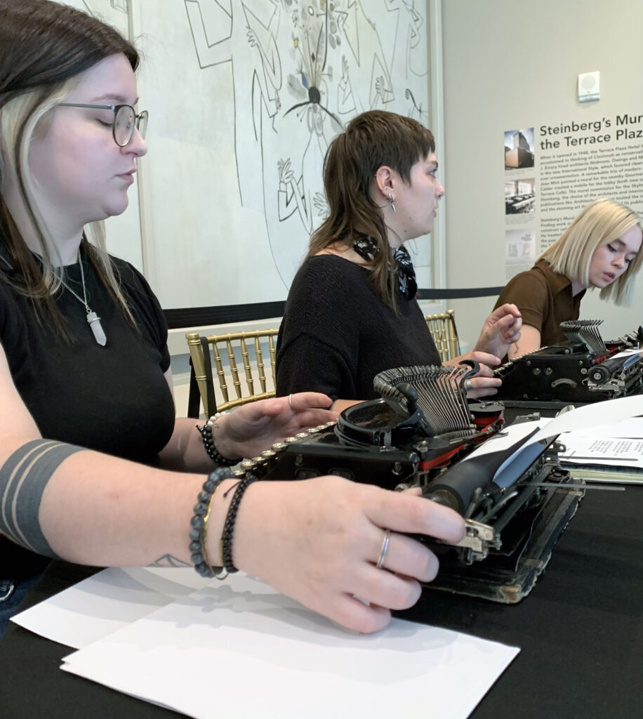 three students typing poems at table