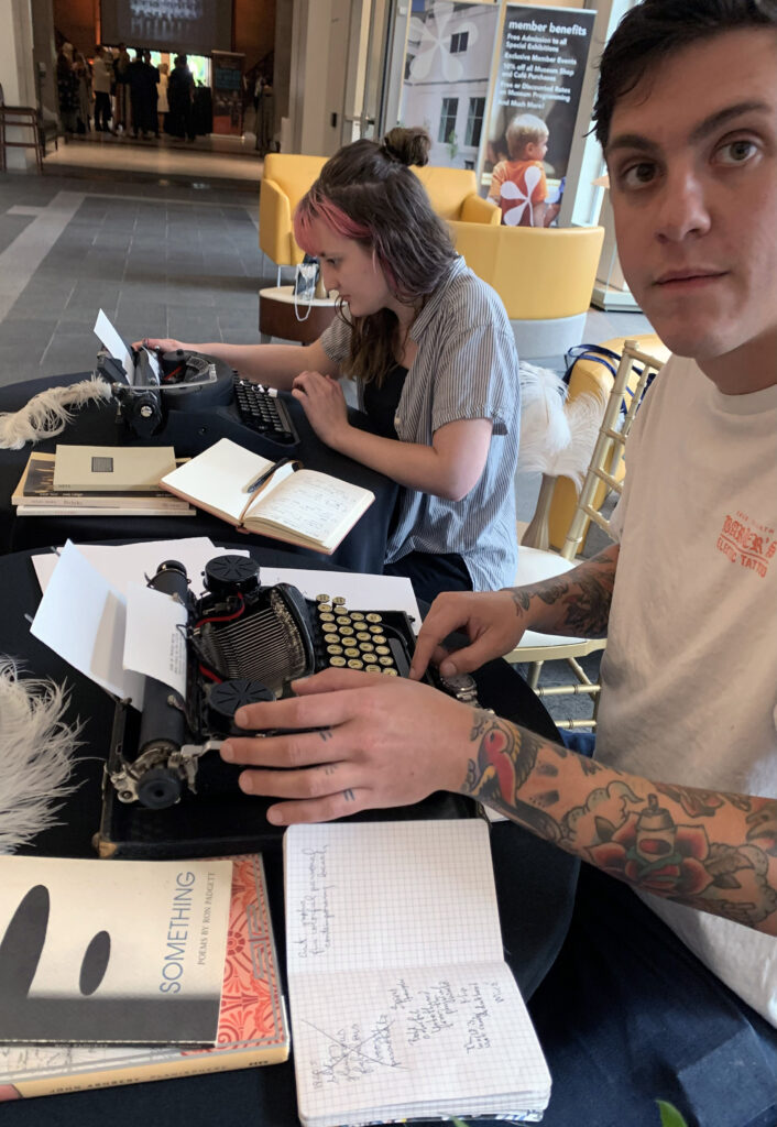 two students typing poems at table