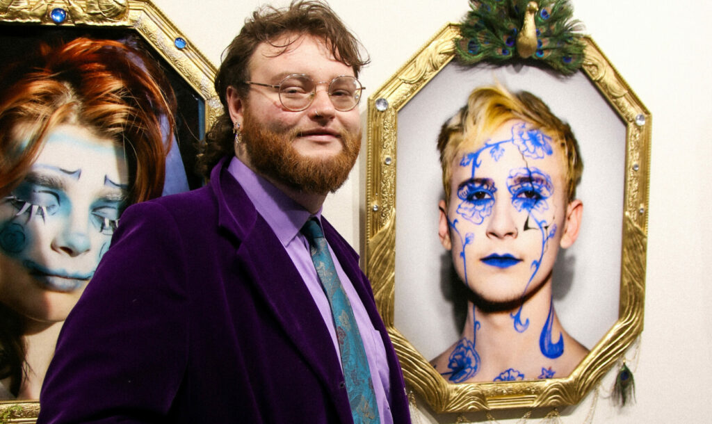 Student standing in front of photographic portraits framed in elaborate frames