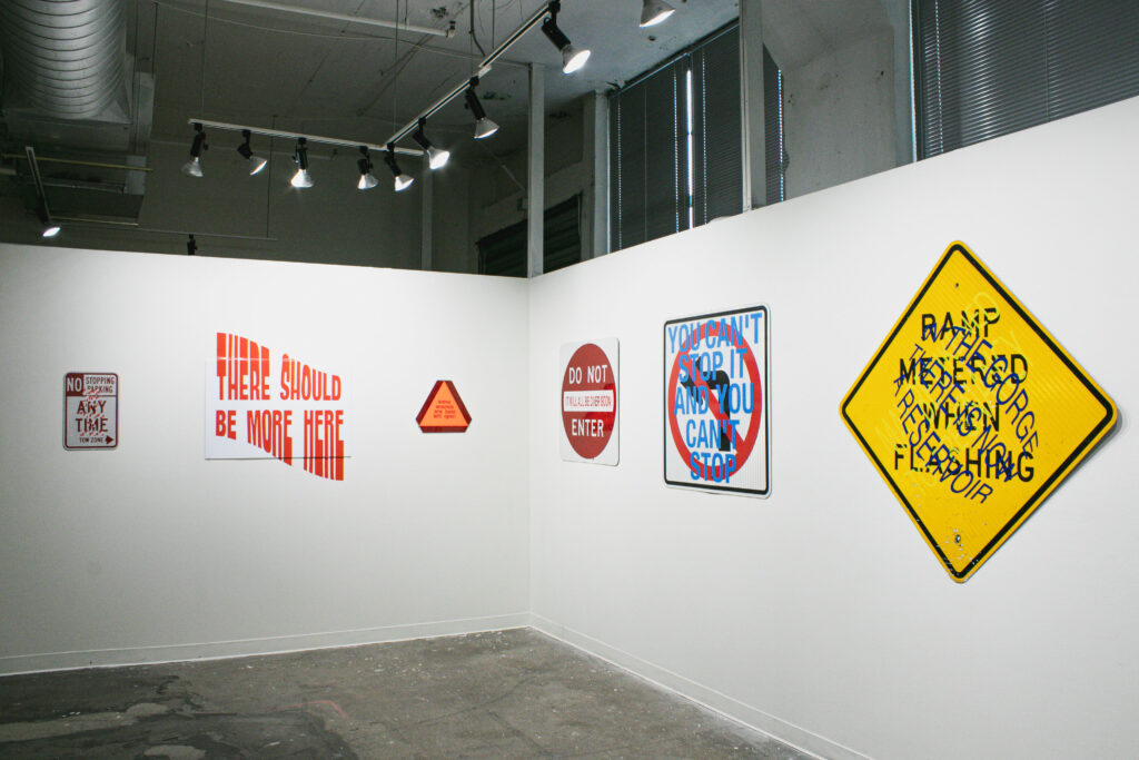 Several printed works on signs hung in a gallery