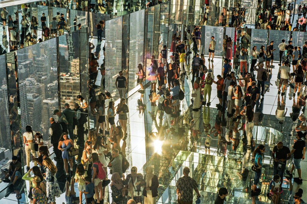 A large crowd in a skyscraper mirrored many times through reflective surfaces