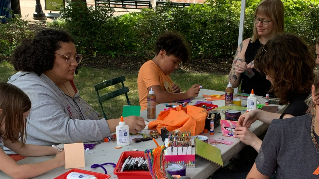 Two women and two children sitting at a table doing arts and crafts