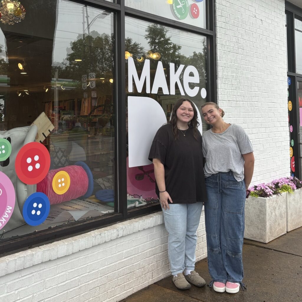 two women standing in front of the store's logo