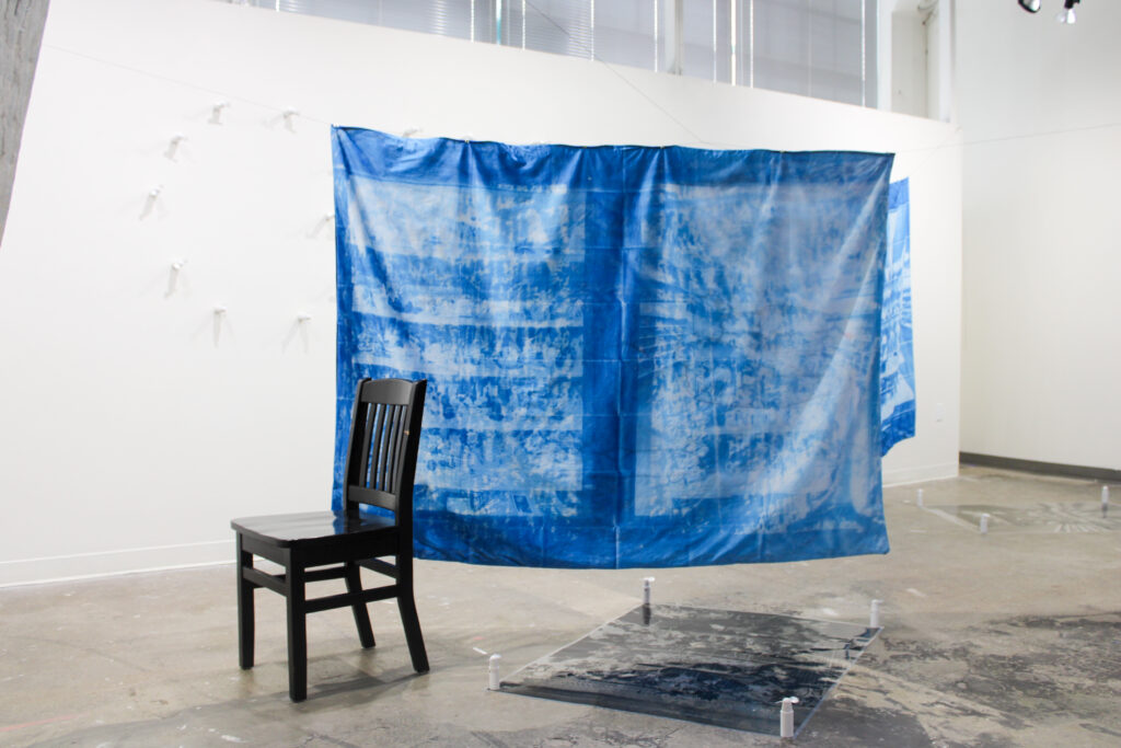 a photo of a gallery displaying a cyanotype artpiece created by tommy ballard