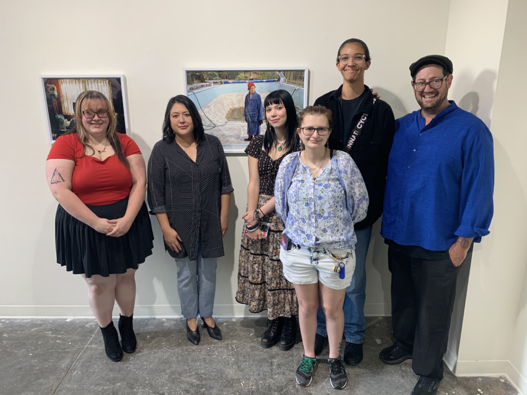 A photo of several students standing together in front of their art; they're accompanied by Joe Girondola, AAC's president.