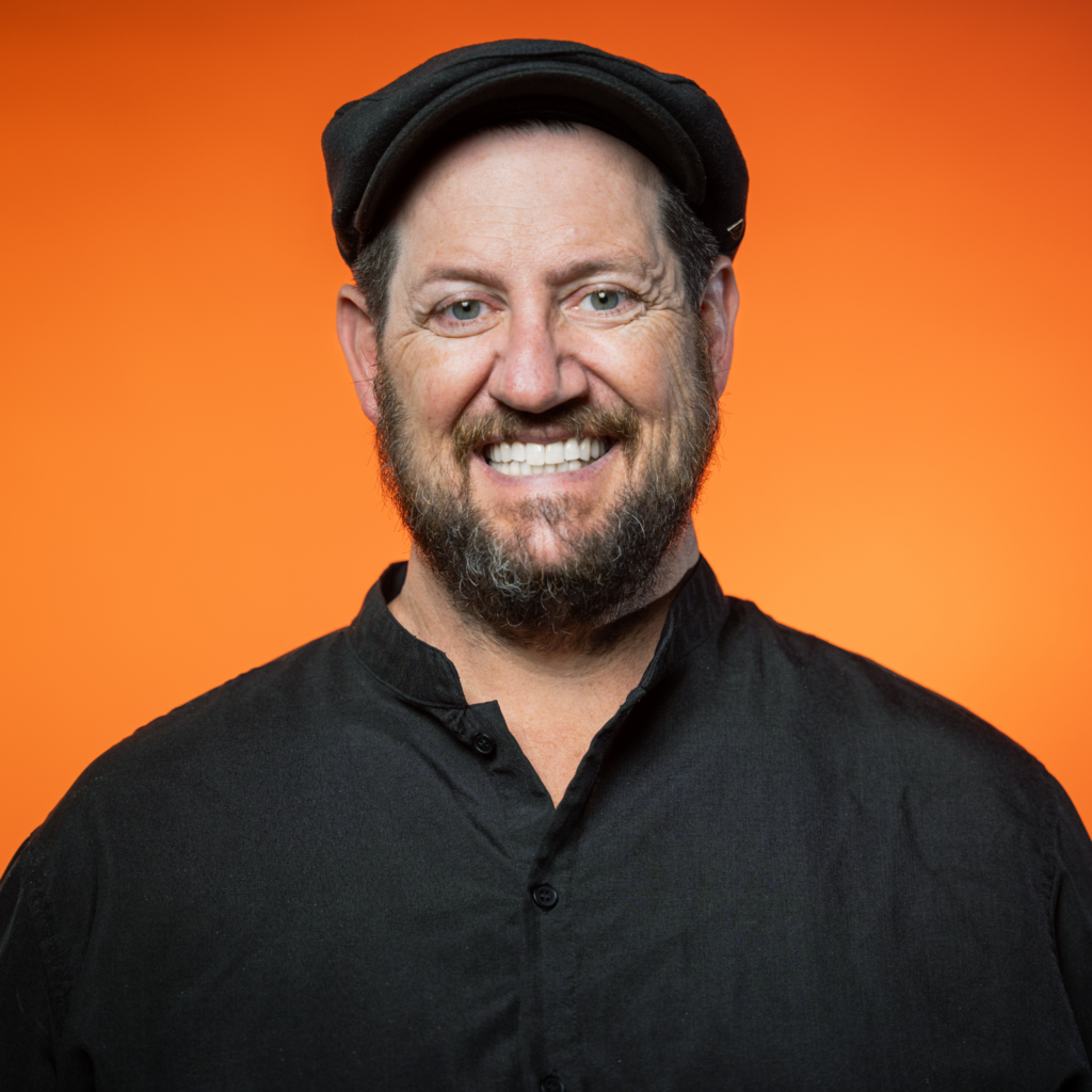 A photo of AAC President Joe Girandola standing in front of a luminescent orange background