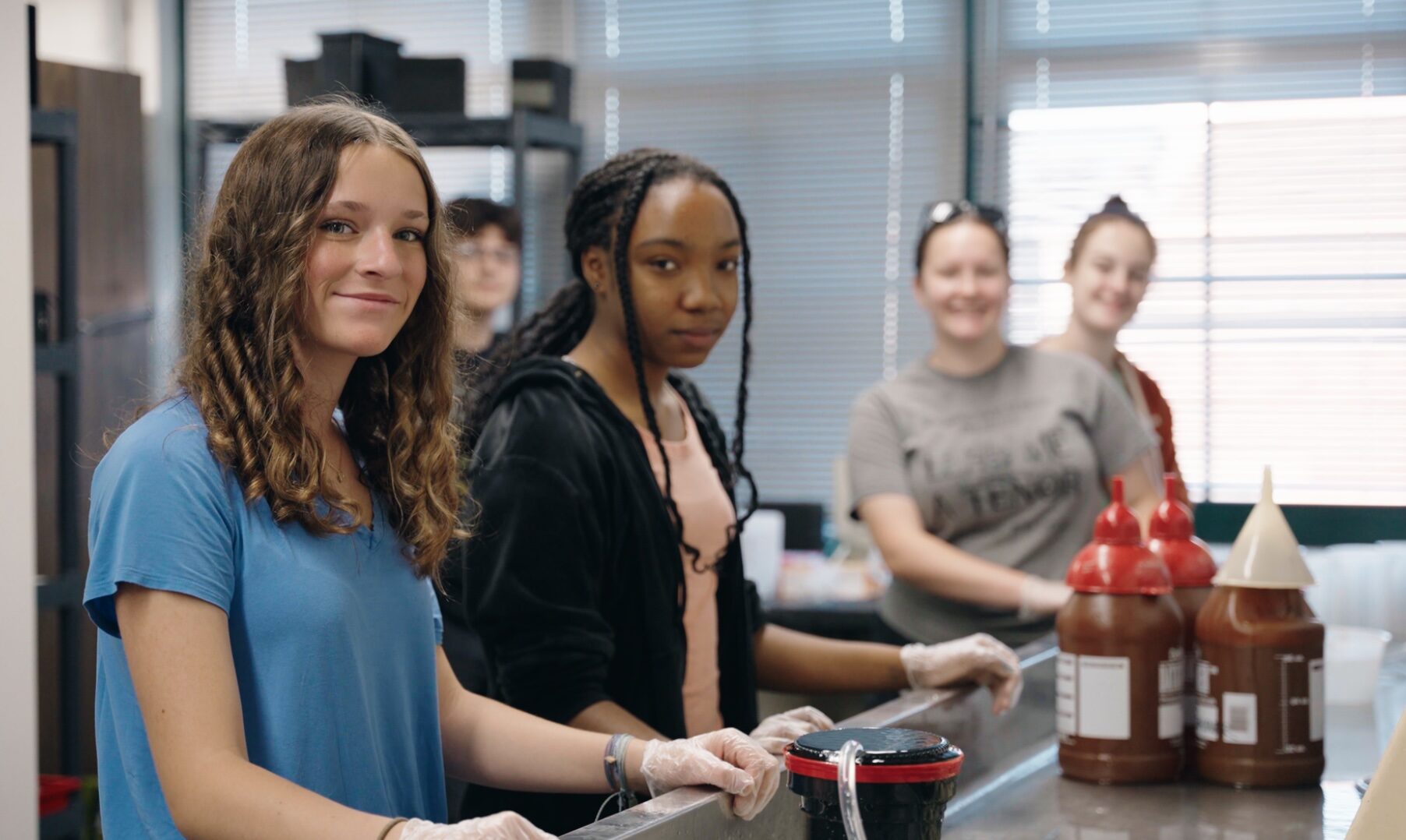 Five students near darkroom sink looking at the camera.